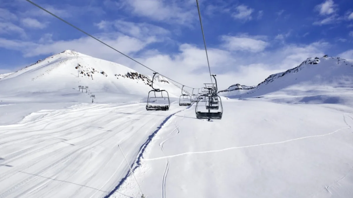 a ski lift going up the side of a snow covered mountain