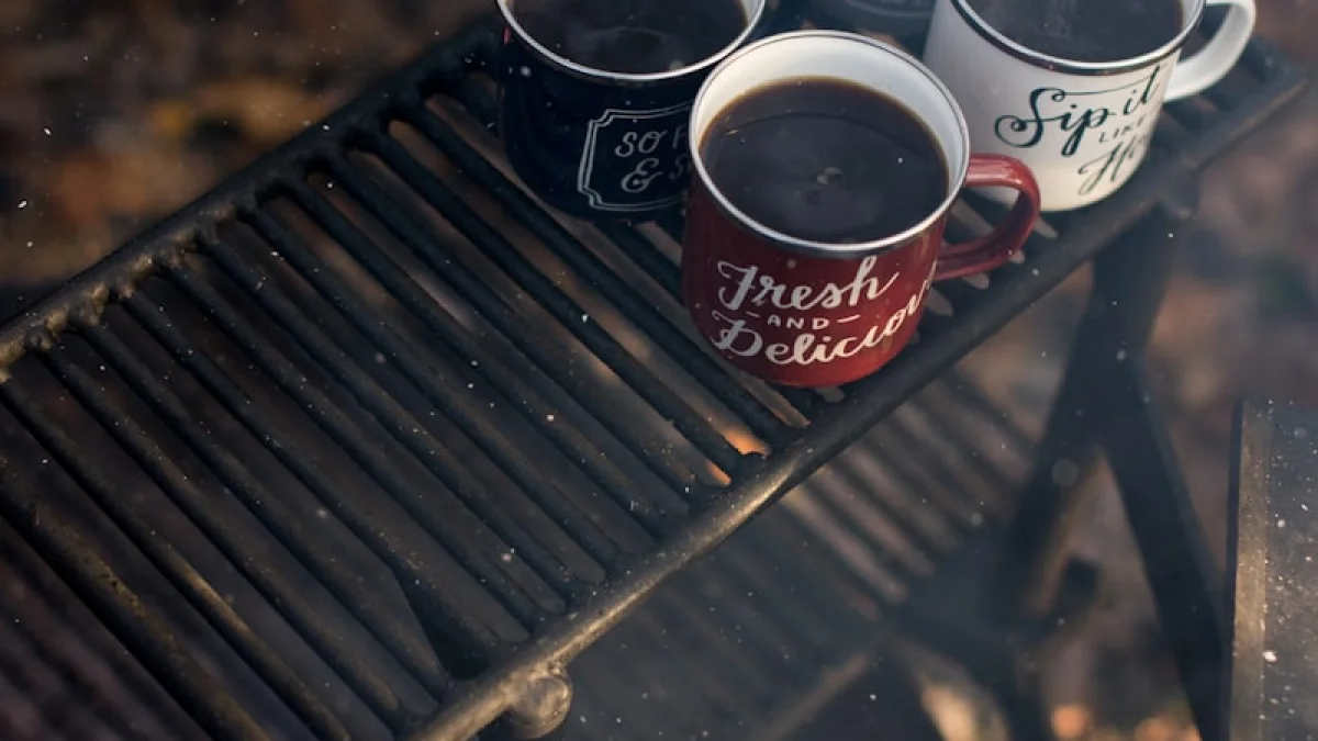 four assorted-color ceramic mugs on black grill frame