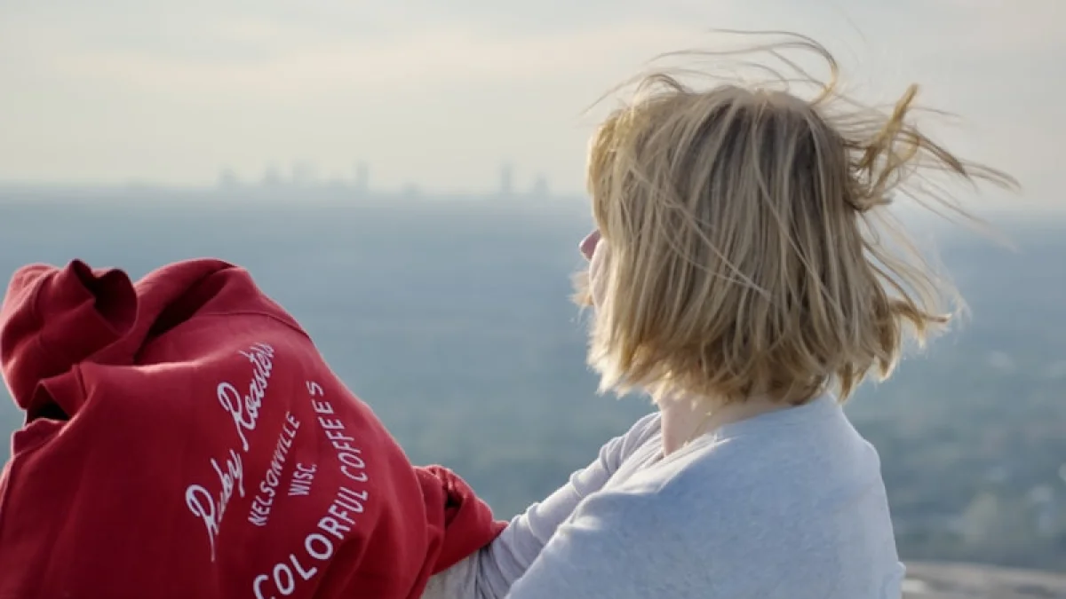 Woman in red sweatshirt overlooking city skyline